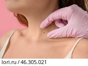Dermatologist examining mole on young woman's neck against pink background, closeup. Стоковое фото, фотограф Pixel_shot / Фотобанк Лори