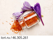 Overturned jar of dried saffron threads and crocus flowers on white table. Стоковое фото, фотограф Pixel_shot / Фотобанк Лори