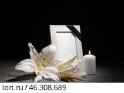 Blank funeral frame, burning candle and flowers on table against dark background. Стоковое фото, фотограф Pixel_shot / Фотобанк Лори