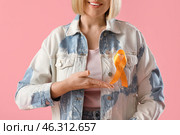 Beautiful mature happy woman pointing at ribbon on pink background, closeup. Multiple Sclerosis Awareness Month. Стоковое фото, фотограф Pixel_shot / Фотобанк Лори