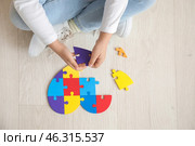 Little girl with autistic disorder doing puzzle on floor, top view. Стоковое фото, фотограф Pixel_shot / Фотобанк Лори