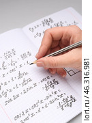 Woman writing maths formulas in copybook with pencil, closeup. Стоковое фото, фотограф Pixel_shot / Фотобанк Лори