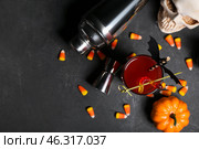 Composition with glass of delicious cocktail, shaker, skull and tasty candy corns for Halloween on dark background. Стоковое фото, фотограф Pixel_shot / Фотобанк Лори