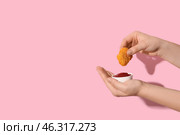 Woman holding tasty nugget and bowl of ketchup on pink background. Стоковое фото, фотограф Pixel_shot / Фотобанк Лори