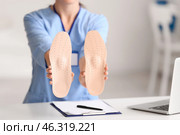 Female nurse holding orthopedic insoles at table. Стоковое фото, фотограф Pixel_shot / Фотобанк Лори