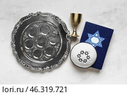 Passover Seder plate, Torah, cup and kippah on light background. Стоковое фото, фотограф Pixel_shot / Фотобанк Лори