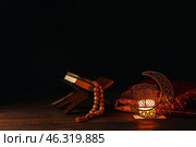 Arabic candle holder with glowing candle, Quran and tasbih on dark background. Стоковое фото, фотограф Pixel_shot / Фотобанк Лори