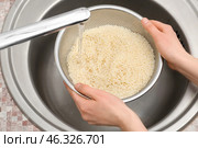 Woman rinsing rice in sifter under running water. Стоковое фото, фотограф Pixel_shot / Фотобанк Лори