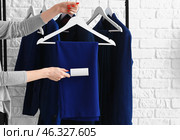 Woman cleaning clothes with lint roller on brick background. Стоковое фото, фотограф Pixel_shot / Фотобанк Лори