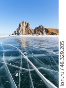 Frozen Baikal Lake. Winter travels to famous Shamanka Rock or Cape Burkhan - natural landmark of Olkhon Island. Scenic winter landscape with blue clear ice with cracks on sunny day in February. Стоковое фото, фотограф Виктория Катьянова / Фотобанк Лори