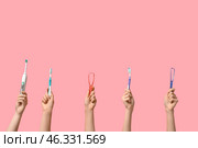 Female hands with toothbrushes and tongue scrapers on pink background. Стоковое фото, фотограф Pixel_shot / Фотобанк Лори