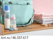 Bottles of milk for baby with pacifiers and clothes on table. Стоковое фото, фотограф Pixel_shot / Фотобанк Лори