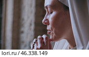 Nun praying with rosary beads in a church. Стоковое видео, видеограф Данил Руденко / Фотобанк Лори