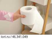 Young woman holding soft toilet paper from shelf in restroom. Стоковое фото, фотограф Pixel_shot / Фотобанк Лори