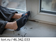 Legs of homeless little girl sitting on window sill. Стоковое фото, фотограф Pixel_shot / Фотобанк Лори