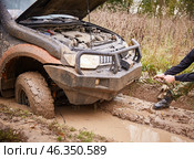 Moscow region, Russia - 28.09.2018. faceless man pulls a car out of the mud on a cable. Adventures on off-road vehicles. The wheels of the car got stuck in a rut and a puddle. Стоковое фото, фотограф Кутина Татьяна / Фотобанк Лори