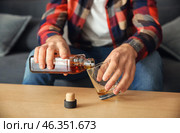 Man pouring alcohol from bottle into glass at table, closeup. Alcoholism concept. Стоковое фото, фотограф Pixel_shot / Фотобанк Лори