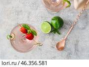 Glasses of tasty cosmopolitan cocktail, limes and spoon on grunge background. Стоковое фото, фотограф Pixel_shot / Фотобанк Лори