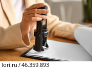 Female notary public attaching seal to document in office, closeup. Стоковое фото, фотограф Pixel_shot / Фотобанк Лори