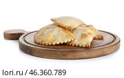 Wooden cutting board with baked meat empanadas on white background. Стоковое фото, фотограф Pixel_shot / Фотобанк Лори