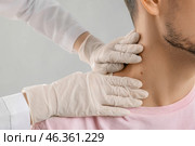 Dermatologist examining mole of young man on grey background, closeup. Стоковое фото, фотограф Pixel_shot / Фотобанк Лори