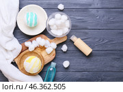 Bowl with cotton balls, cosmetics and bath bombs on grey wooden background. Стоковое фото, фотограф Pixel_shot / Фотобанк Лори