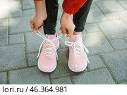 Woman in stylish sneakers tying shoe lace outdoors, closeup. Стоковое фото, фотограф Pixel_shot / Фотобанк Лори