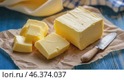 Fresh yellow butter sliced on wood cutting board. Cut butter block and pieces on a rustic table, blue linen napkin. Assortment of natural organic butter for breakfast. Baking ingredient. Close up view. Стоковое AI-видео, аниматор Марина Демидюк / Фотобанк Лори