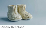 Close up of textile baby booties. Pregnancy concept, Pairs of baby shoes on a blue background. Gender neutral baby garment and accessories. Organic newborn bootie, fashion, branding. Gender neutral. Стоковое AI-видео, аниматор Марина Демидюк / Фотобанк Лори