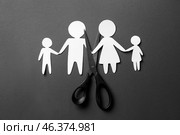 Scissors with paper figures of family on dark background. Concept of divorce. Стоковое фото, фотограф Pixel_shot / Фотобанк Лори