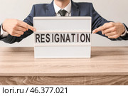 Man pointing at board with text RESIGNATION at table. Стоковое фото, фотограф Pixel_shot / Фотобанк Лори