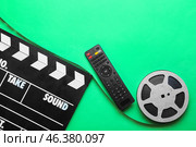 Modern TV remote control with film reel and clapperboard on green background. Стоковое фото, фотограф Pixel_shot / Фотобанк Лори