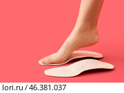 Female foot and orthopedic insoles on red background. Стоковое фото, фотограф Pixel_shot / Фотобанк Лори