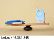 Office supplies with baby monitor on teeterboard against light background. Concept of balance. Стоковое фото, фотограф Pixel_shot / Фотобанк Лори