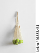 String shopping bag with ripe bergamot fruits hanging on light wall. Стоковое фото, фотограф Pixel_shot / Фотобанк Лори