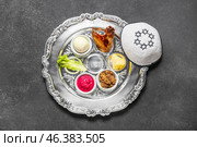 Passover Seder plate with traditional food and kippah on dark background. Стоковое фото, фотограф Pixel_shot / Фотобанк Лори