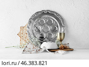Passover Seder plate with cup of wine, kippah and matza on white background. Стоковое фото, фотограф Pixel_shot / Фотобанк Лори