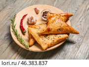 Plate with tasty Uzbek samsa and spices on wooden background. Стоковое фото, фотограф Pixel_shot / Фотобанк Лори