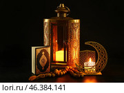 Arabic candle holder with glowing candle, fanoos lamp, Quran and tasbih on dark background. Стоковое фото, фотограф Pixel_shot / Фотобанк Лори