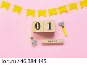 Composition with party whistles and cube calendar with date 1 APRIL on pink background. April Fools Day celebration. Стоковое фото, фотограф Pixel_shot / Фотобанк Лори