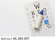 Container with contact lenses, solution and eye test chart on white background. Стоковое фото, фотограф Pixel_shot / Фотобанк Лори
