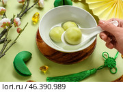 Female hand with spoon and bowl of tangyuan on green background, closeup. Dongzhi Festival. Стоковое фото, фотограф Pixel_shot / Фотобанк Лори