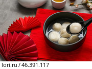 Red mat with bowl of tangyuan and Chinese decor on grey grunge background, closeup. Dongzhi Festival. Стоковое фото, фотограф Pixel_shot / Фотобанк Лори