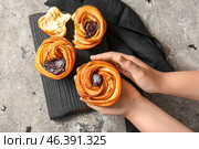 Woman eating tasty cruffins with chocolate on grey background. Стоковое фото, фотограф Pixel_shot / Фотобанк Лори