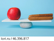 Apple and cigars on teeterboard against color background. Concept of balance. Стоковое фото, фотограф Pixel_shot / Фотобанк Лори