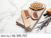 Hair combs, massage brush, towel and bottle of cosmetic product on light background. Стоковое фото, фотограф Pixel_shot / Фотобанк Лори