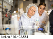 Focused female researchers mixing reagents in test tube with lab pipette while working in laboratory. Стоковое фото, фотограф Яков Филимонов / Фотобанк Лори