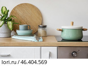 Wooden counter with clean dishes, houseplant, cooking pot and electric stove. Стоковое фото, фотограф Pixel_shot / Фотобанк Лори