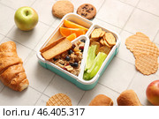 Lunchboxes with different delicious food on white tile background. Стоковое фото, фотограф Pixel_shot / Фотобанк Лори