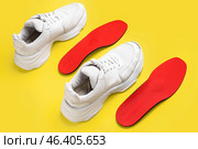 Pair of stylish sneakers and orthopedic insoles on yellow background. Стоковое фото, фотограф Pixel_shot / Фотобанк Лори